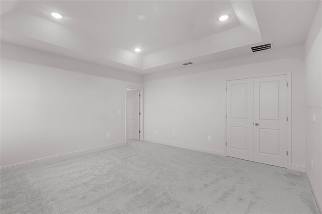 unfurnished room with light carpet and a tray ceiling