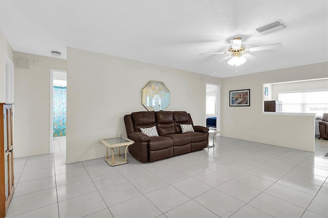 living room with ceiling fan, a textured ceiling, and light tile patterned floors