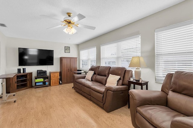 living room with a textured ceiling, ceiling fan, and light hardwood / wood-style flooring