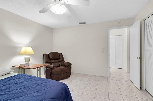 tiled bedroom with ceiling fan, a closet, and a textured ceiling