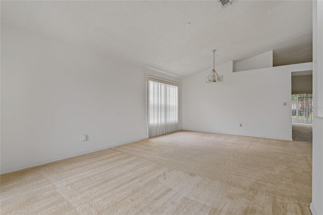 spare room with visible vents, light colored carpet, lofted ceiling, a textured ceiling, and a chandelier