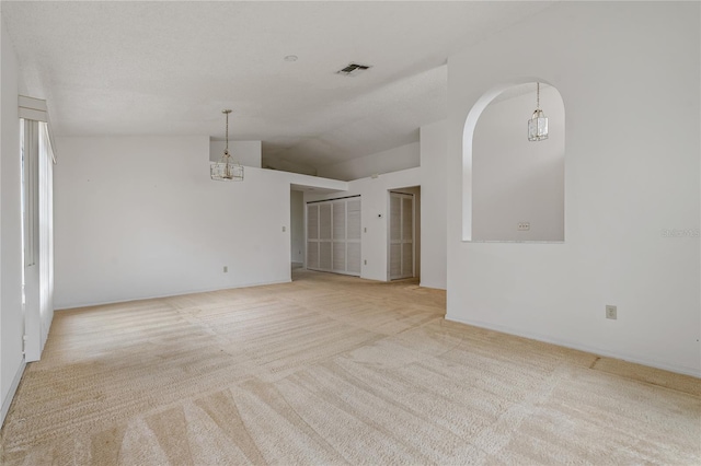 empty room with visible vents, vaulted ceiling, and light colored carpet