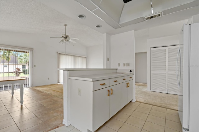 kitchen featuring light colored carpet, light countertops, visible vents, white cabinets, and light tile patterned flooring