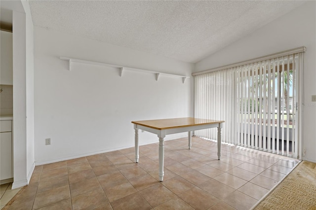 unfurnished dining area with vaulted ceiling, a textured ceiling, and light tile patterned flooring