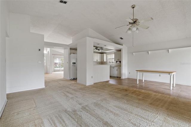 unfurnished living room featuring vaulted ceiling, a wealth of natural light, a ceiling fan, and light colored carpet