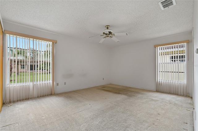 empty room with light carpet, ceiling fan, a textured ceiling, and visible vents