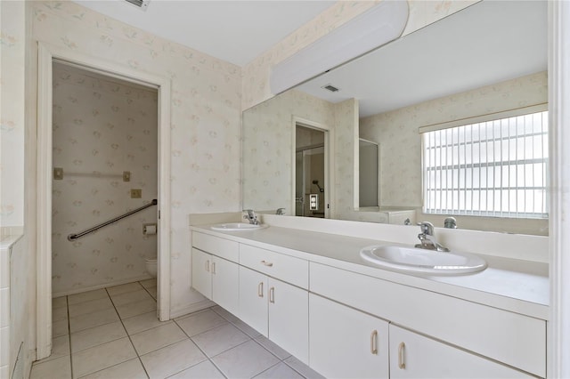 bathroom featuring toilet, wallpapered walls, a sink, and tile patterned floors