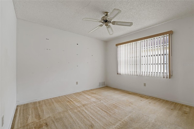 spare room with light colored carpet, ceiling fan, and a textured ceiling