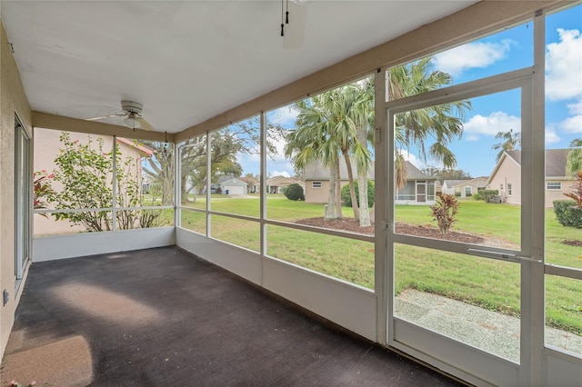 unfurnished sunroom featuring a residential view and a ceiling fan