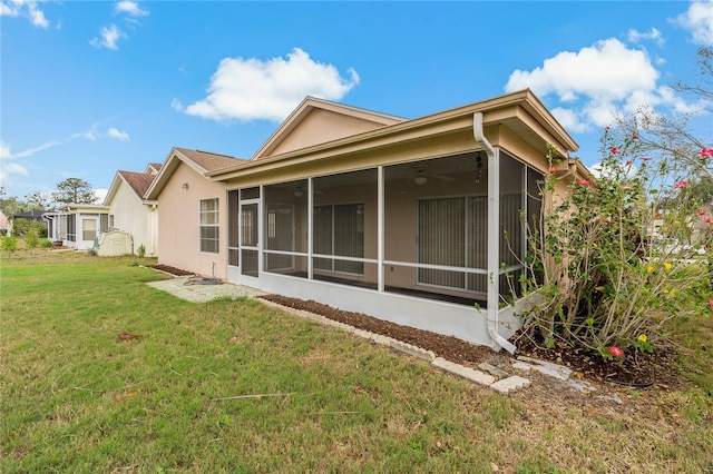 rear view of property with a sunroom, a lawn, and stucco siding