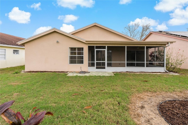 back of property with a sunroom, a yard, and stucco siding