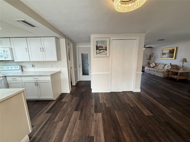 kitchen featuring dark wood-type flooring, white appliances, white cabinets, and ceiling fan with notable chandelier