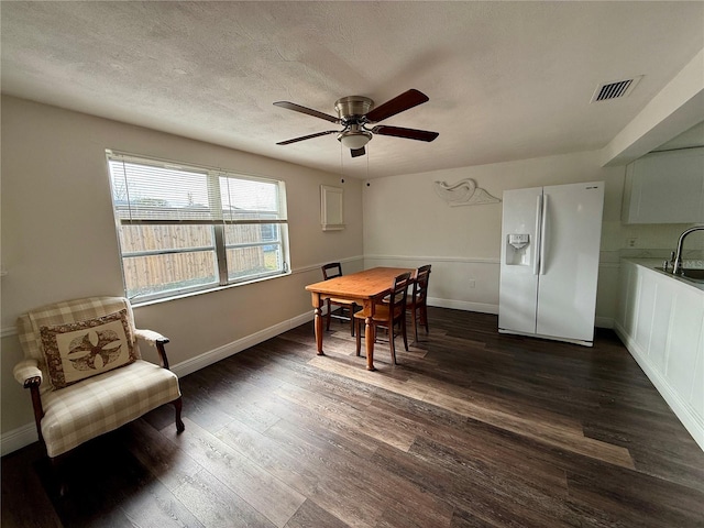 dining space with ceiling fan, dark hardwood / wood-style flooring, a textured ceiling, and sink