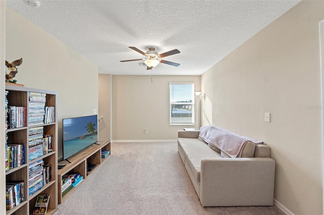 living room with ceiling fan, light colored carpet, and a textured ceiling