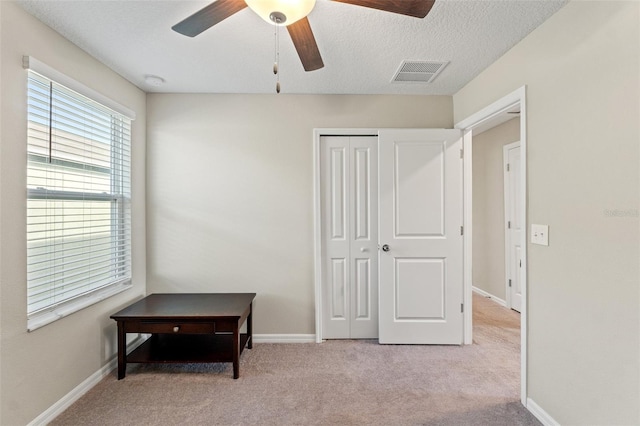 carpeted bedroom featuring a textured ceiling, a closet, and ceiling fan