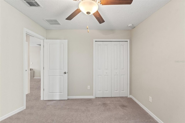 unfurnished bedroom featuring ceiling fan, a closet, light carpet, and a textured ceiling