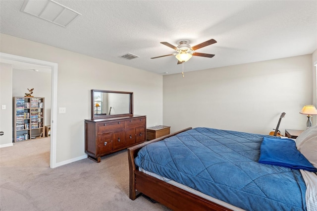 bedroom featuring a textured ceiling, light colored carpet, and ceiling fan