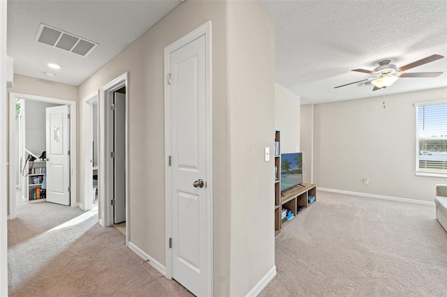 hall featuring light colored carpet and a textured ceiling