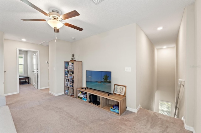 living room with ceiling fan, light colored carpet, and a textured ceiling