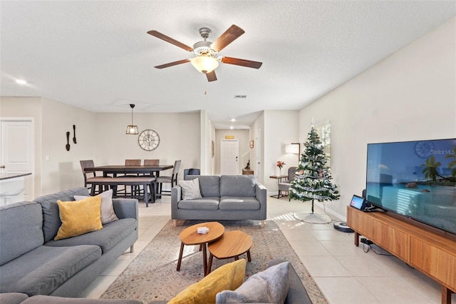 living room featuring a textured ceiling, ceiling fan, and light tile patterned flooring