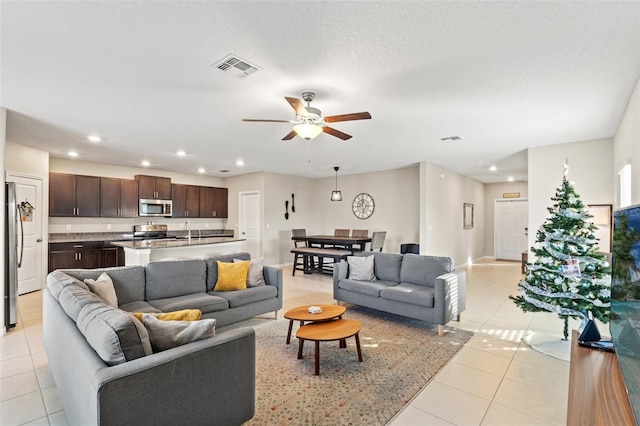 living room with light tile patterned floors, a textured ceiling, and ceiling fan