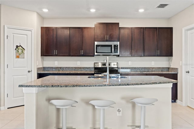 kitchen featuring a kitchen island with sink, a breakfast bar, sink, and appliances with stainless steel finishes