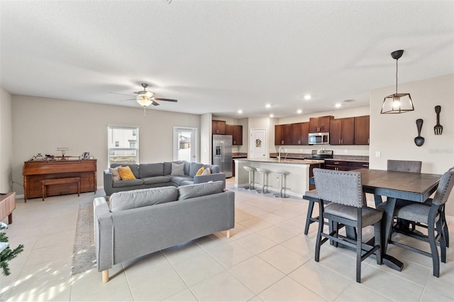 tiled living room with ceiling fan, sink, and a textured ceiling