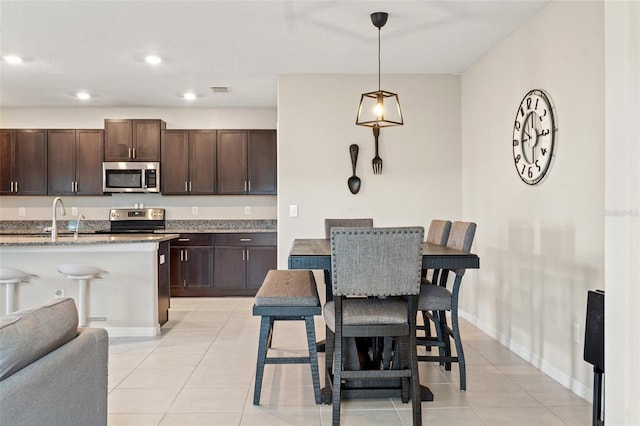 kitchen with light stone countertops, stove, light tile patterned flooring, and decorative light fixtures