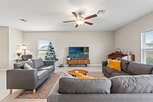 living room with light tile patterned floors, a textured ceiling, ceiling fan, and a healthy amount of sunlight