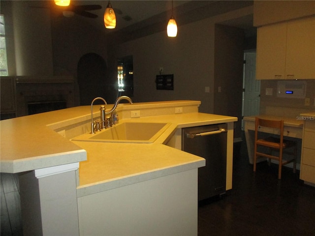 kitchen with sink, hanging light fixtures, stainless steel dishwasher, ceiling fan, and an island with sink