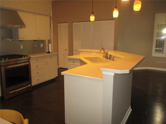 kitchen featuring stainless steel range with electric stovetop, a center island with sink, sink, range hood, and decorative light fixtures