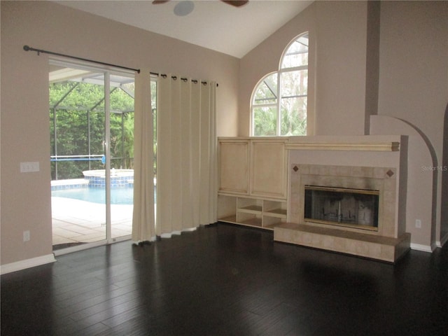 unfurnished living room with a fireplace, vaulted ceiling, ceiling fan, and dark wood-type flooring