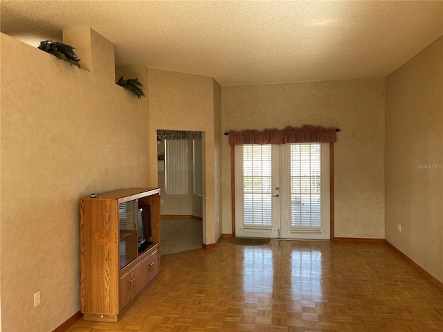 unfurnished living room featuring french doors, light parquet floors, and a textured ceiling