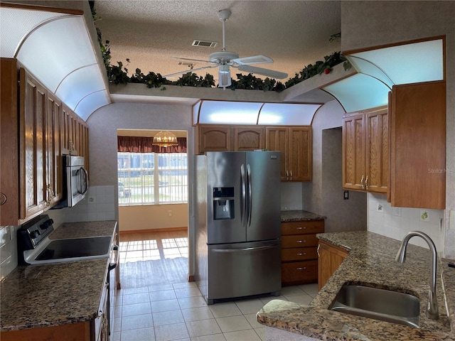 kitchen featuring sink, stainless steel appliances, a textured ceiling, decorative backsplash, and ceiling fan with notable chandelier