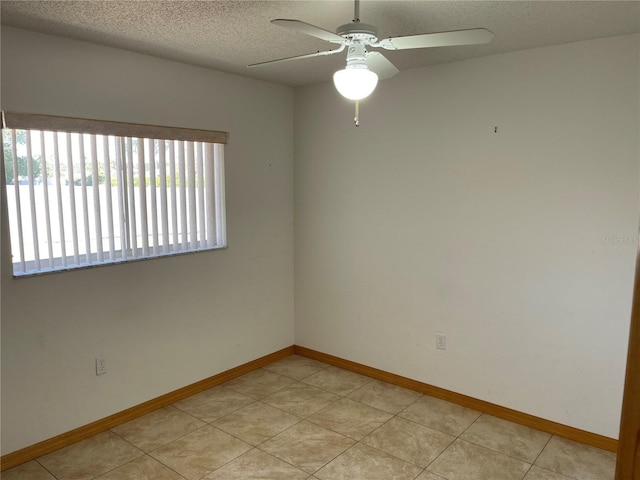 unfurnished room with ceiling fan, light tile patterned flooring, and a textured ceiling