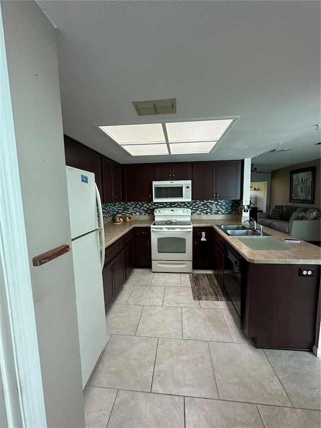 kitchen with white appliances, sink, kitchen peninsula, light tile patterned flooring, and dark brown cabinetry