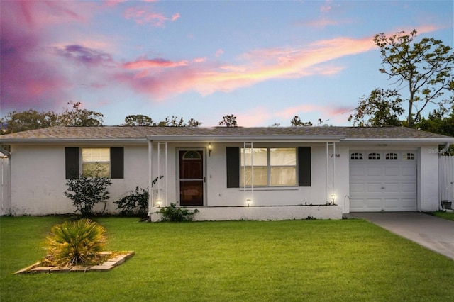 single story home featuring a garage and a lawn