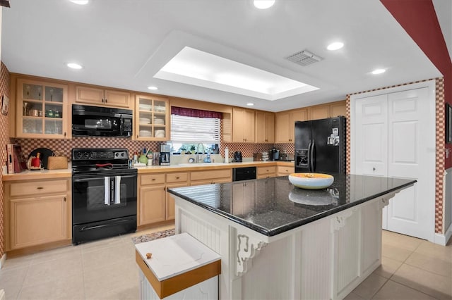 kitchen featuring tasteful backsplash, a breakfast bar, black appliances, a kitchen island, and light tile patterned flooring