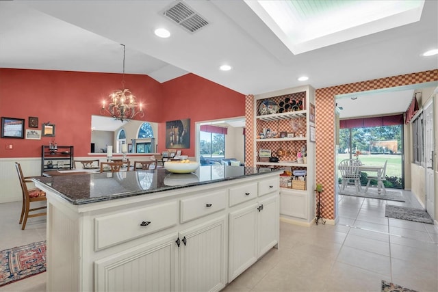 kitchen with a kitchen island, lofted ceiling, a wealth of natural light, and dark stone counters