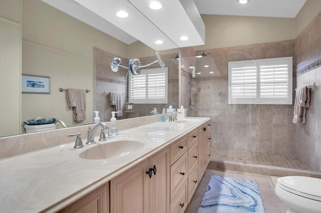 bathroom with tile patterned flooring, lofted ceiling, toilet, tiled shower, and vanity