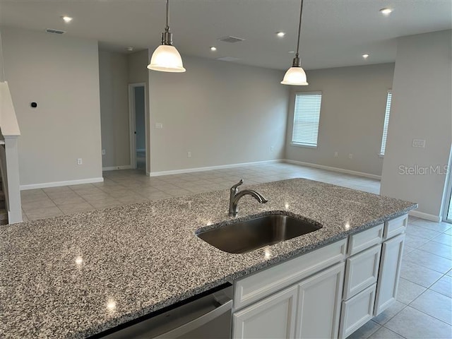 kitchen featuring light stone countertops, white cabinetry, hanging light fixtures, and sink