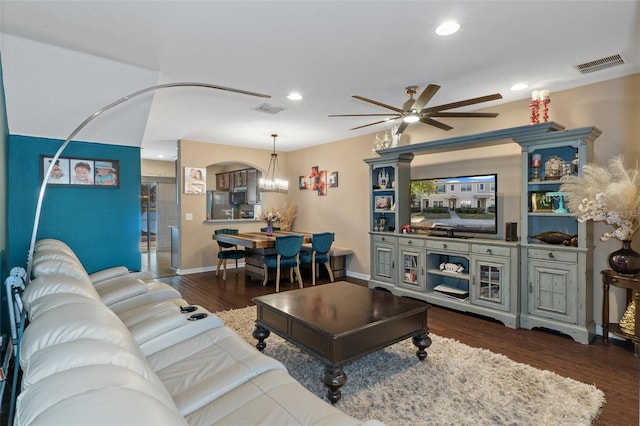 living room with ceiling fan with notable chandelier and dark hardwood / wood-style floors