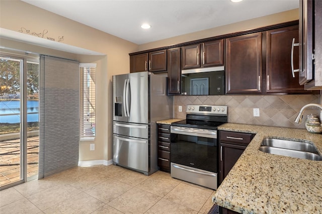 kitchen featuring sink, decorative backsplash, appliances with stainless steel finishes, light stone counters, and dark brown cabinetry