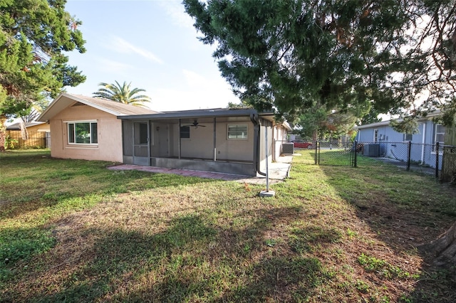 back of property with a sunroom, ceiling fan, and a lawn