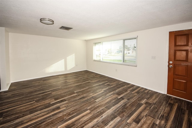 unfurnished room with a textured ceiling and dark wood-type flooring