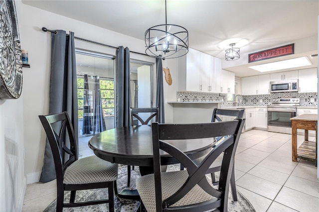 tiled dining space featuring sink and a chandelier