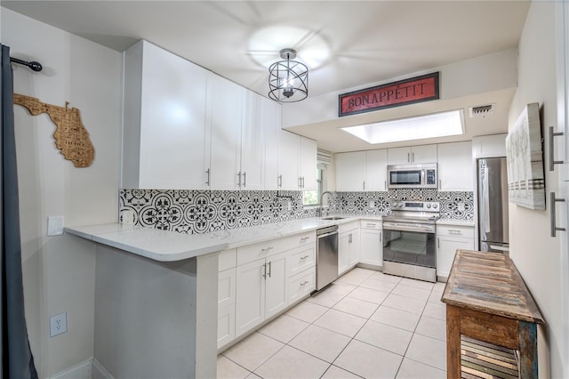 kitchen with decorative backsplash, stainless steel appliances, sink, light tile patterned floors, and white cabinets