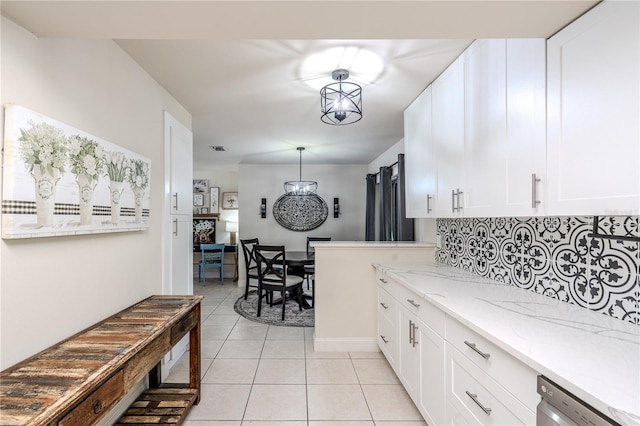 kitchen featuring white cabinets, light tile patterned floors, decorative light fixtures, and stainless steel dishwasher