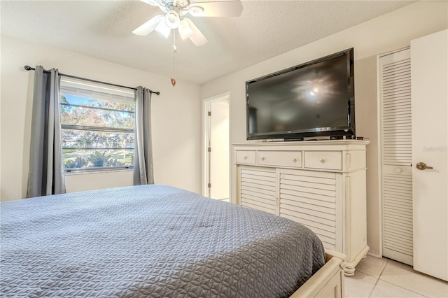 bedroom with ceiling fan, light tile patterned flooring, and a textured ceiling