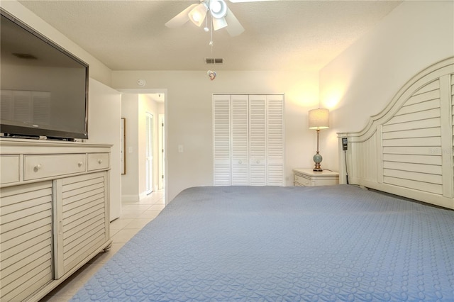 bedroom with light tile patterned floors, a textured ceiling, a closet, and ceiling fan